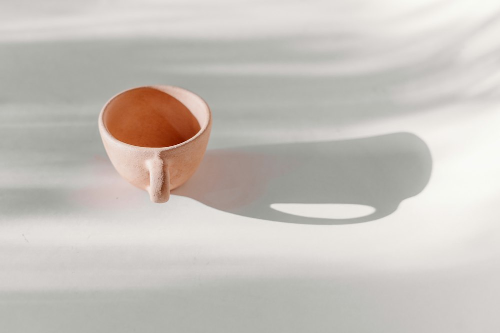 Braune Keramiktasse auf einem weißen Tisch